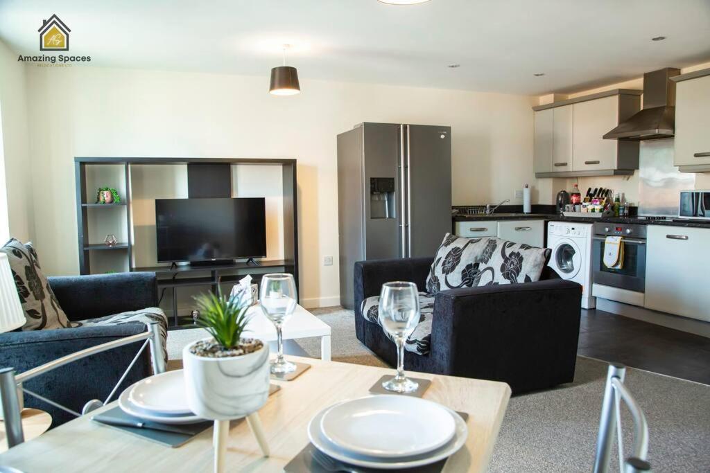 a living room with a couch and a table with wine glasses at Homely 2 Bed Flat Sleeps 4 with Parking and Wifi by Amazing Spaces Relocations Ltd in Warrington