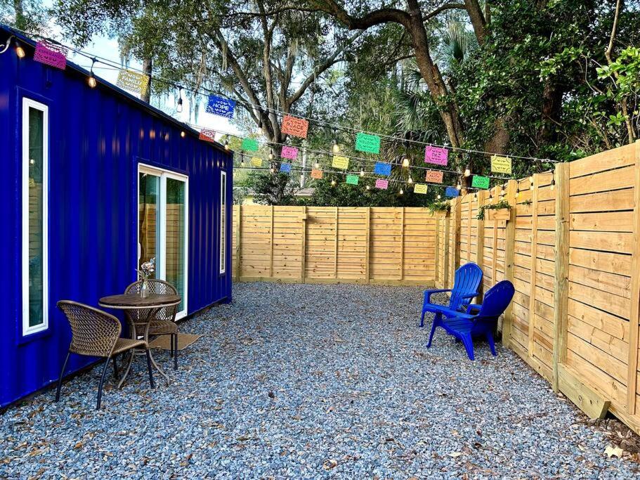 a blue house with chairs and a table and a fence at Entirely Private Tiny Home - 1 Mile to UF in Gainesville