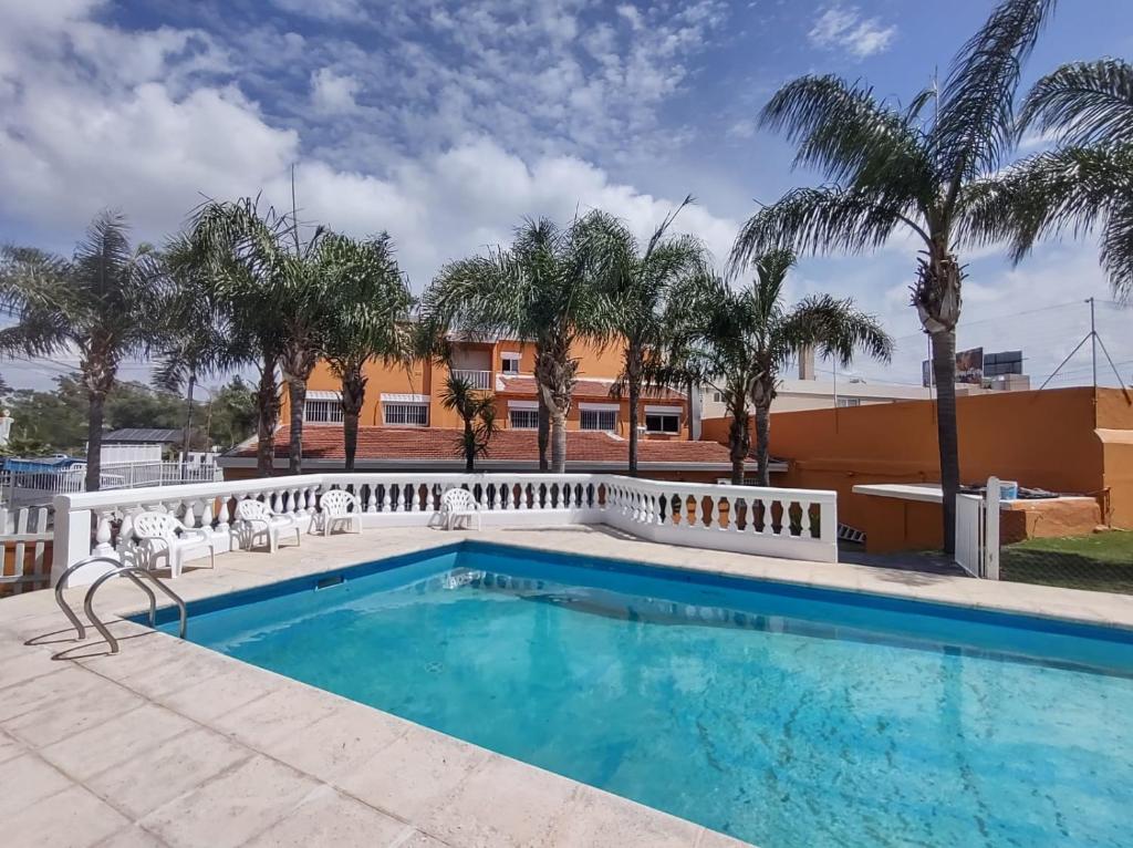 una piscina con palmeras y un edificio en Saint Tropez hotel en Villa Carlos Paz