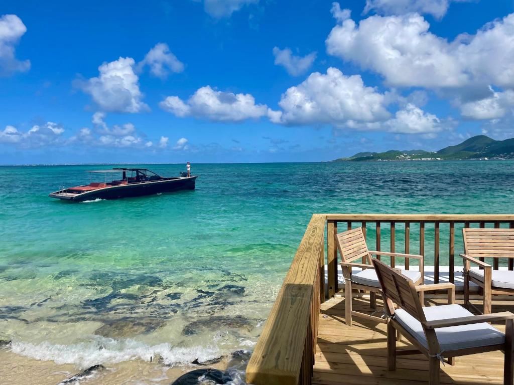 a boat in the water next to chairs on a dock at La Plage Bleue feet in the water with swimming pool in Baie Nettle