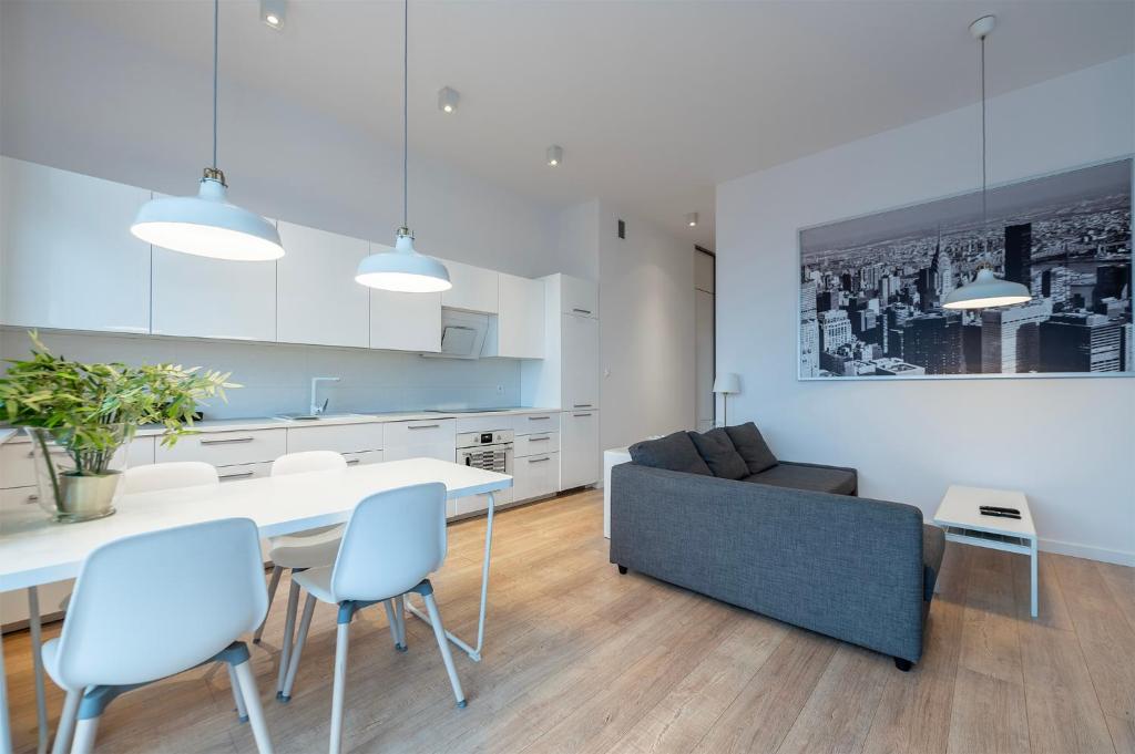 een keuken en een woonkamer met een tafel en stoelen bij Penthouse with a View of Lodz & Free Parking in Łódź