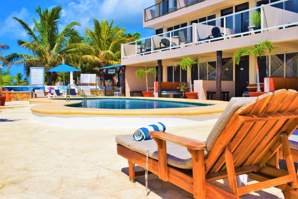 un complejo con piscina, silla y edificio en Hacienda Morelos Beachfront Hotel, en Puerto Morelos