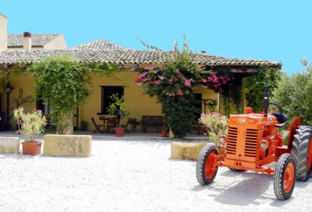 un tractor naranja estacionado frente a una casa en Agriturismo Baglio Vecchio, en Castelvetrano Selinunte