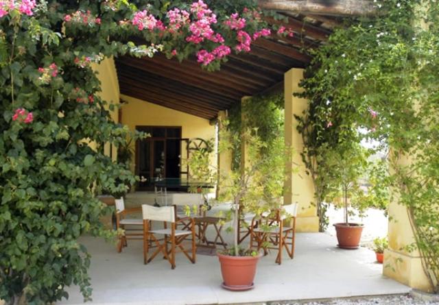 a patio with a table and chairs and pink flowers at Agriturismo Baglio Vecchio in Castelvetrano Selinunte