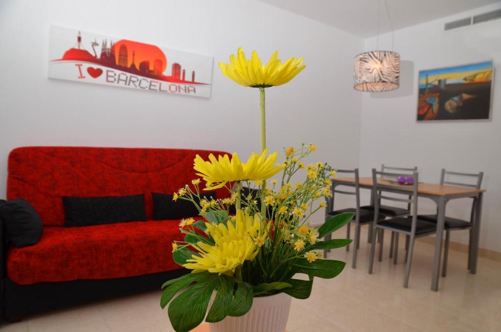 バルセロナにあるアパルタメントス ナバス 2の赤いソファと黄色い花が飾られたリビングルーム