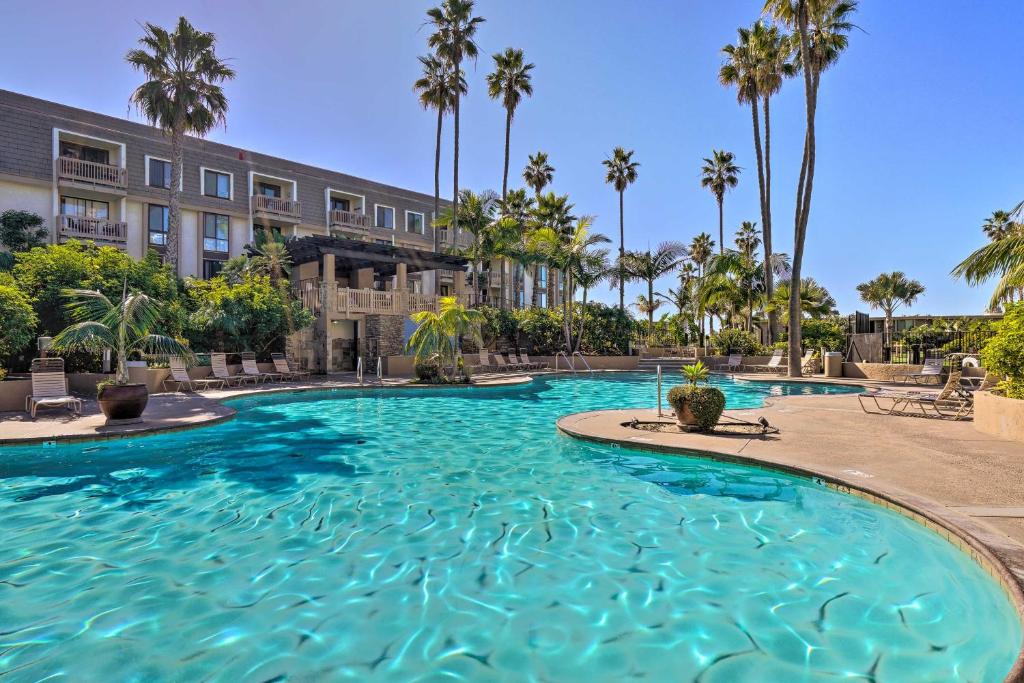 a swimming pool with palm trees and a building at Beachfront Oceanside Condo with Amenity Access! in Oceanside