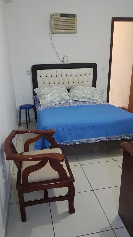 a bedroom with a bed with blue sheets and a chair at Hospedagem 20m da praia. in Itapema