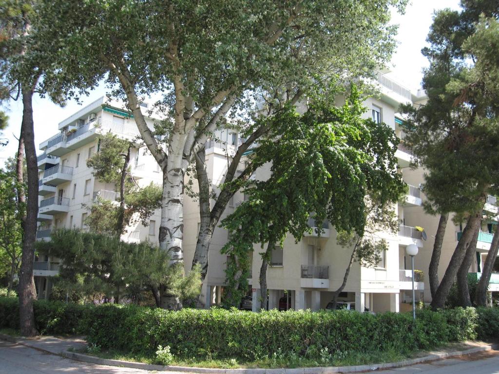 un edificio bianco con alberi di fronte di Appartamento Due Stelle a Grado
