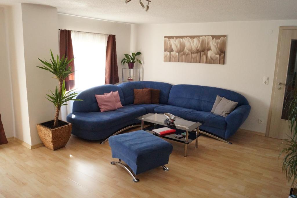 un soggiorno con divano blu e tavolo di Ferienwohnungen Denk a Niederalteich