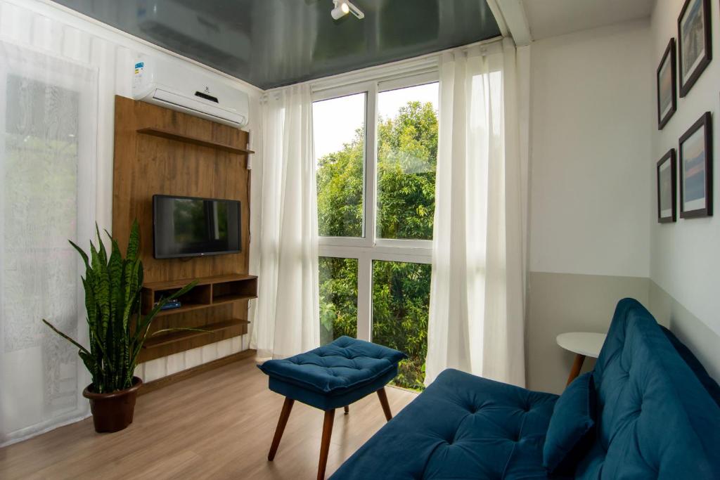 sala de estar con sofá azul y ventana en Casa Container Incrível no Campeche, 2 hóspedes SUL91 en Florianópolis