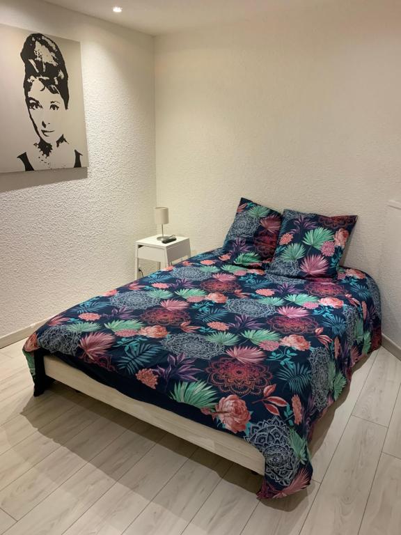 sypialnia z łóżkiem z kwiecistą kołdrą w obiekcie Appartement 1er Etage 42m2 hyper centre ville / parking gratuit w mieście Riom