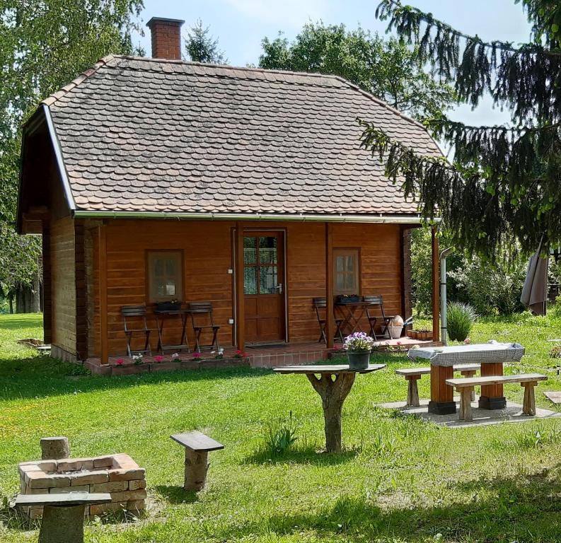 Cabaña de madera pequeña con mesa de picnic y bancos en Kiskemence Vendégház Szatta, en Szatta
