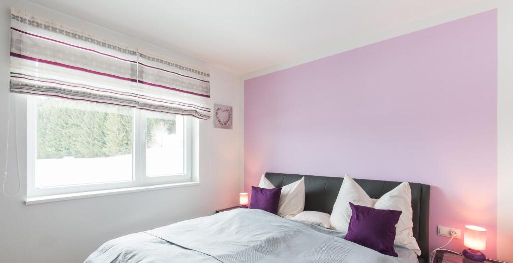 a bedroom with a bed with purple pillows and a window at Appartement Klosterhügel in Haus im Ennstal