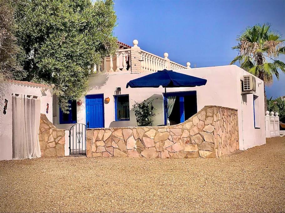 a white house with a blue door and a stone wall at Casa Alegria in Antas