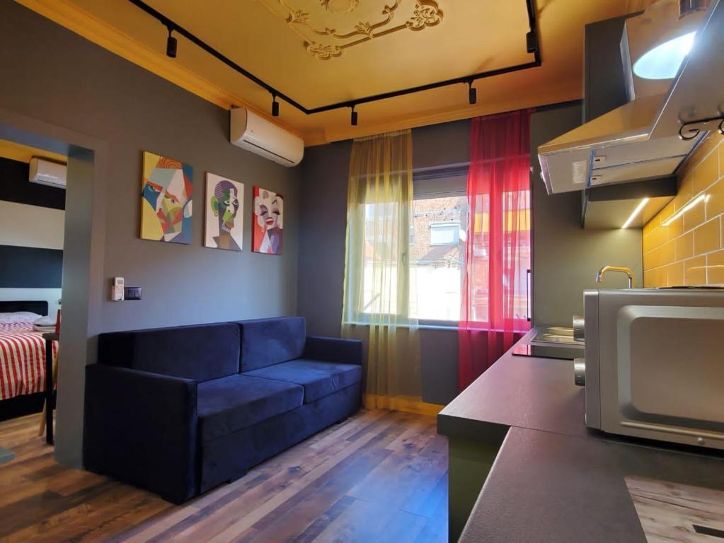 ein Wohnzimmer mit einer blauen Couch in einer Küche in der Unterkunft Helga’s Sunset apartment in Tirana