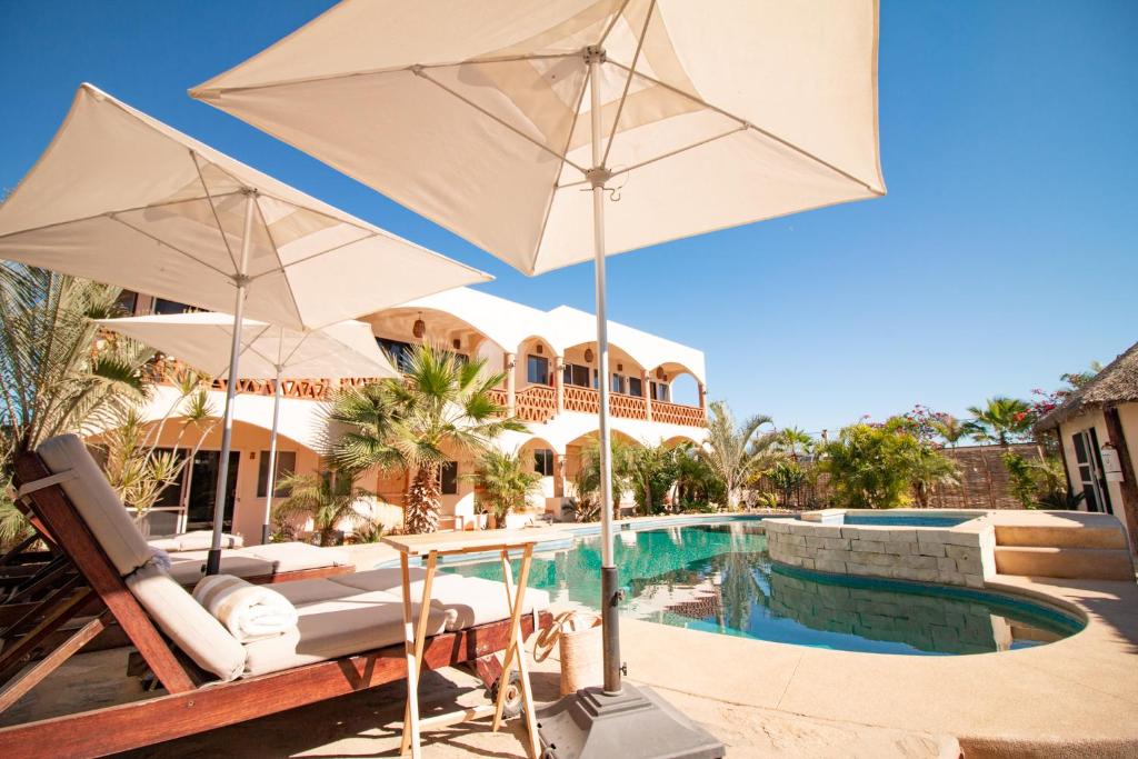 a pool with two white umbrellas next to a house at Olas de Cerritos in El Pescadero