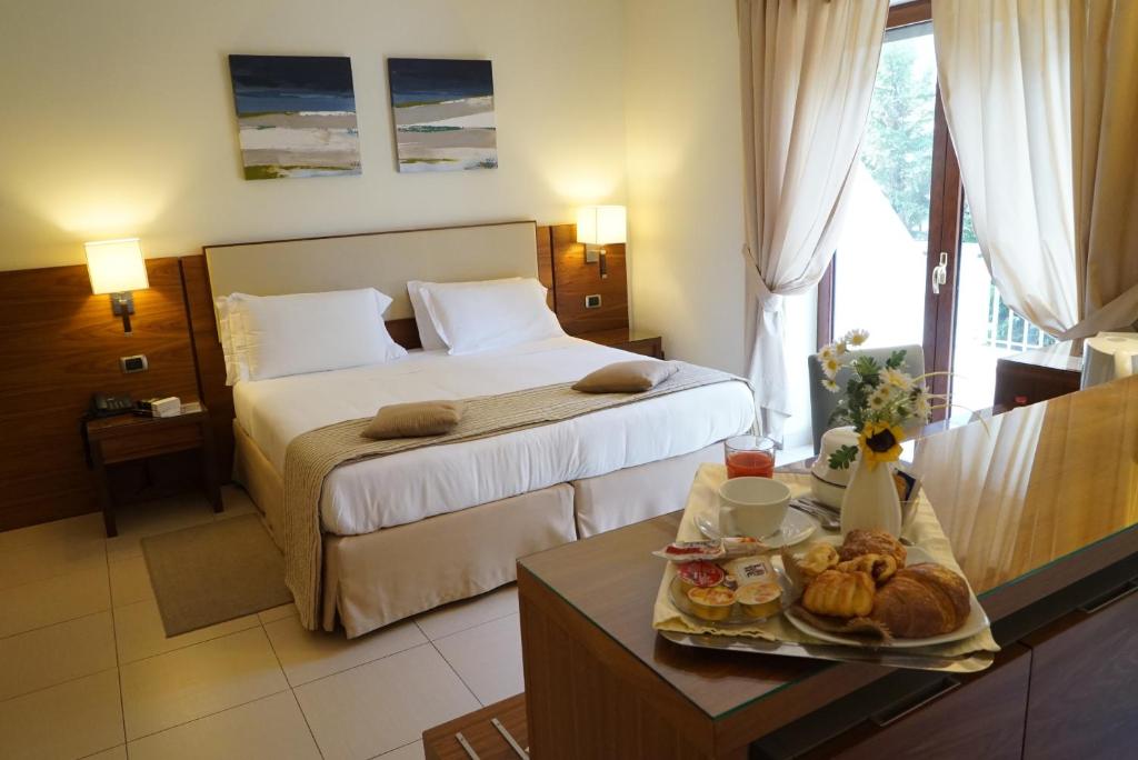 ein Hotelzimmer mit einem Bett und einem Tisch mit Essen in der Unterkunft Suites & Residence Hotel in Pozzuoli