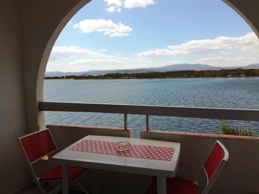 une table et des chaises sur un balcon avec vue sur l'eau dans l'établissement Superbe vue sur le chenal, à Leucate