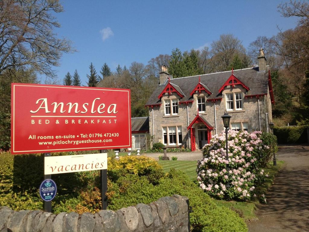 un cartel delante de una casa con un cartel en Annslea Guest House en Pitlochry