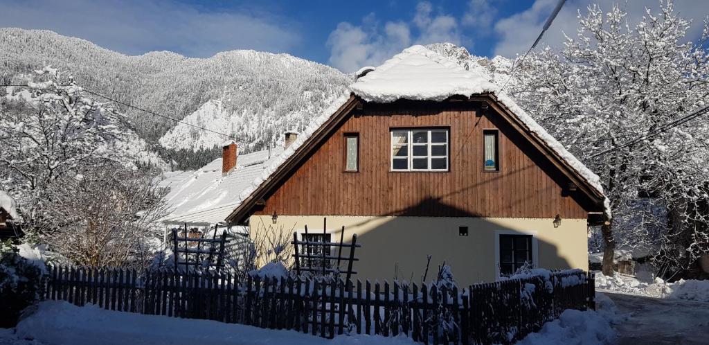 una casa con techo cubierto de nieve y valla en The OldMillhouse, en Mojstrana