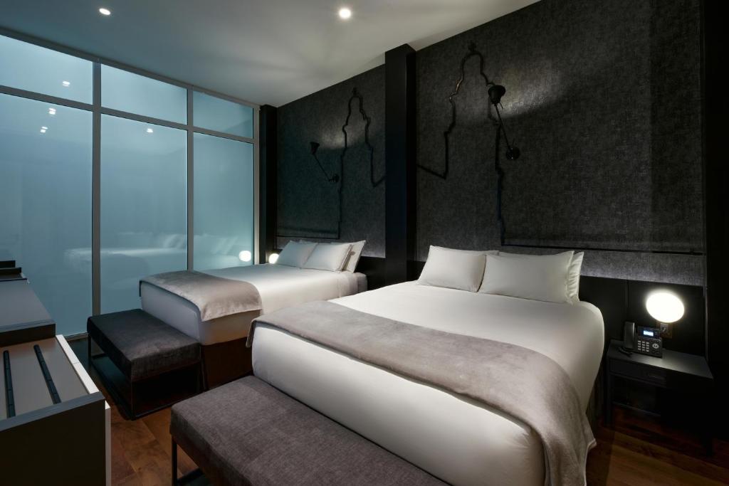 a hotel room with two beds and a window at Casa Firenza Hotel & Suites Boutique in Cuenca