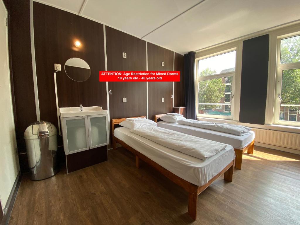 una habitación con 3 camas y un cartel que dice: en Hostel Utopia, en Ámsterdam