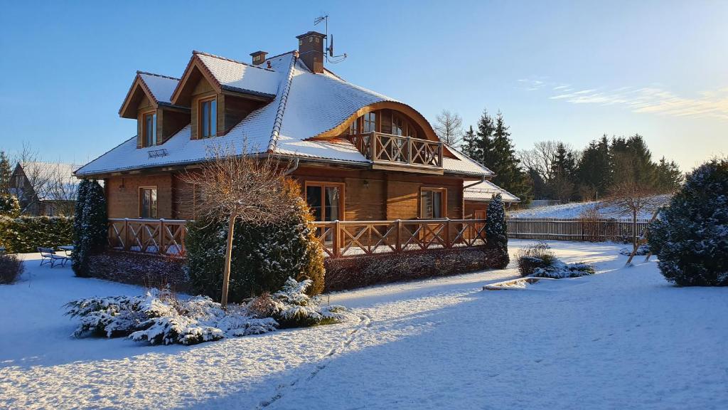 una gran casa de madera con nieve en el techo en Villa Morela, en Mikołajki