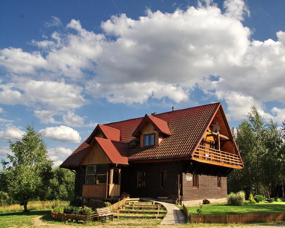 une maison en bois avec un toit rouge sur un champ dans l'établissement Puszcza Romincka, à Galwiecie