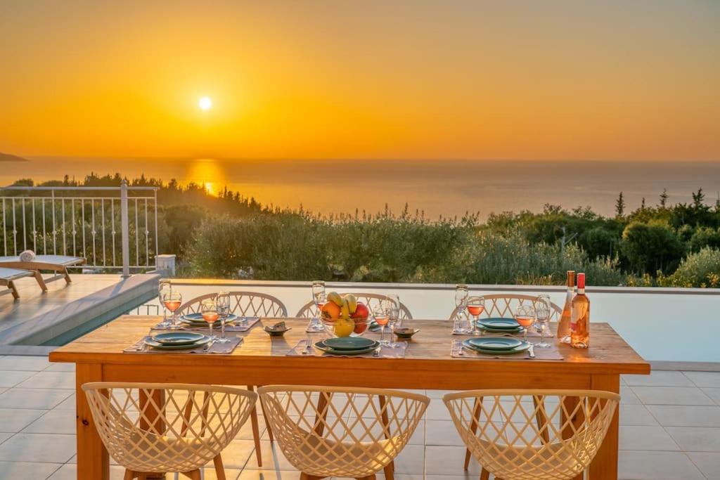 a table on a balcony with a sunset in the background at Fiscardo Luxury Stone Villa Suzana ,with sunset view! in Fiskardho