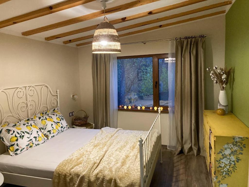 een slaapkamer met een wit bed en een raam bij Къща за гости ЗЕЛЕНА in Vinogradets