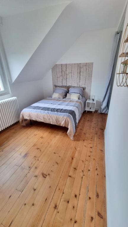 1 dormitorio con 1 cama y suelo de madera en Chambre meublée 2ème R en Saint-Quentin