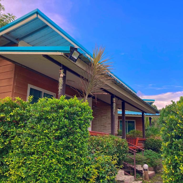 a house with a blue roof and some bushes at Labelle House in Ko Lanta