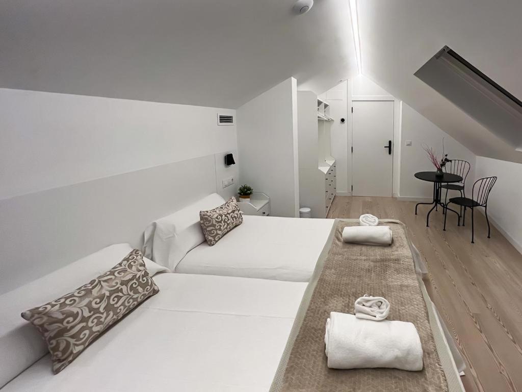 龐特維德拉的住宿－Hostel Charino，白色的客房设有一张大床和一张桌子。