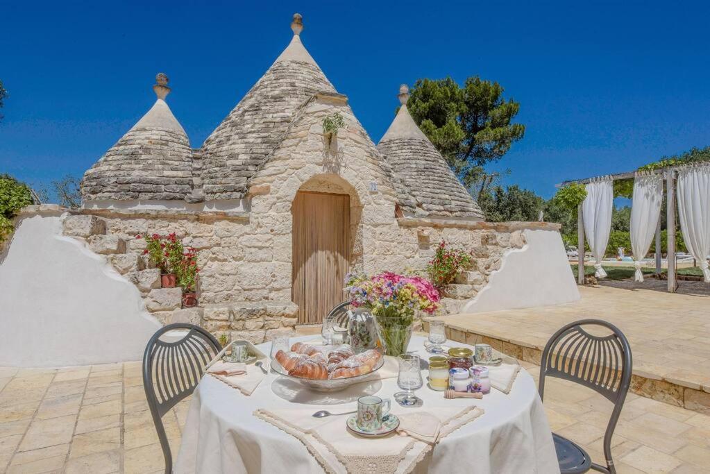 una mesa con un bol de fruta y un edificio en TRULLO CHEFMARCO PRIVATE/SALTWATER SWIMMING POOL, en San Michele Salentino
