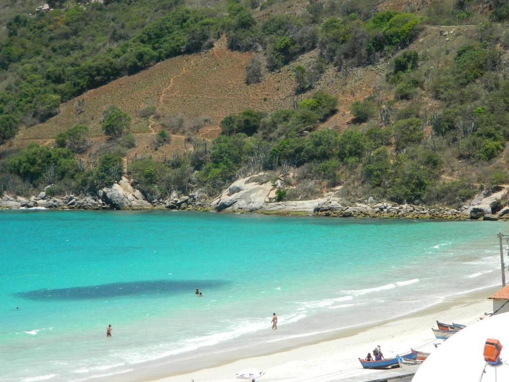 a beach with blue water and two boats on it at Loft Prainha Arraial in Arraial do Cabo