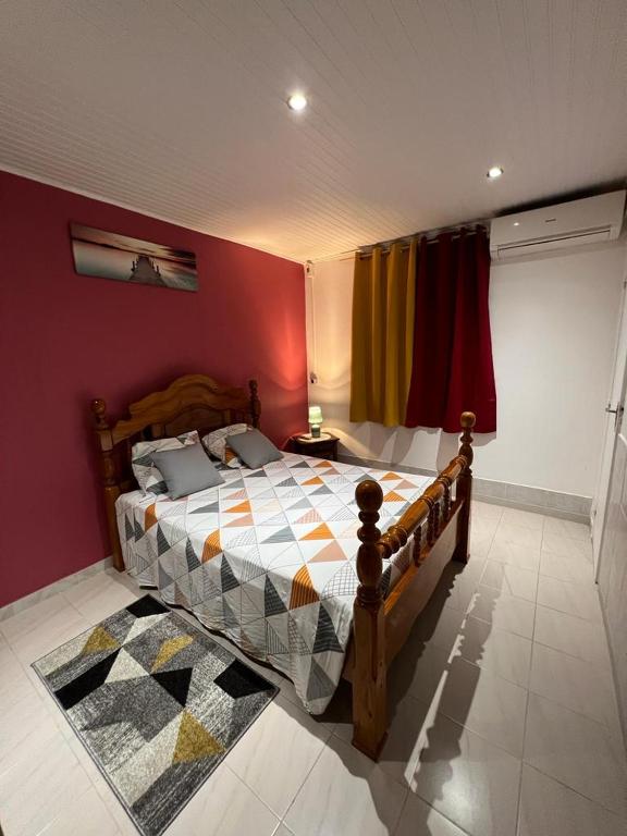 ein Schlafzimmer mit einem Holzbett mit einer farbenfrohen Wand in der Unterkunft Poseidon in Le Lamentin