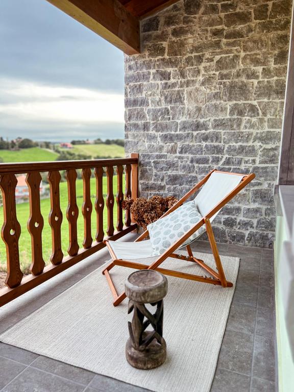 a rocking chair on a porch with a stone wall at Alto el Monte 2 - AR1414 in Bocines