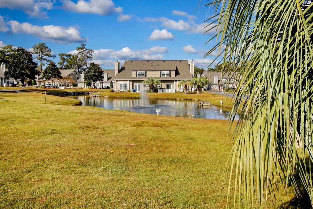 a house with a pond in front of a house at Fairway Oaks Getaway in Myrtle Beach