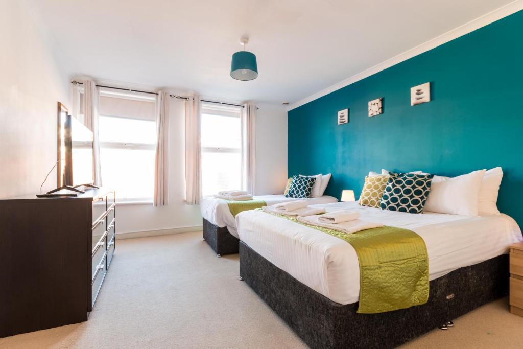Duas camas num quarto com uma parede azul em Old Town Apartments em Swindon