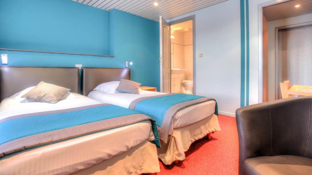 a hotel room with two beds and a chair at Hotel Le Terminus in Mons
