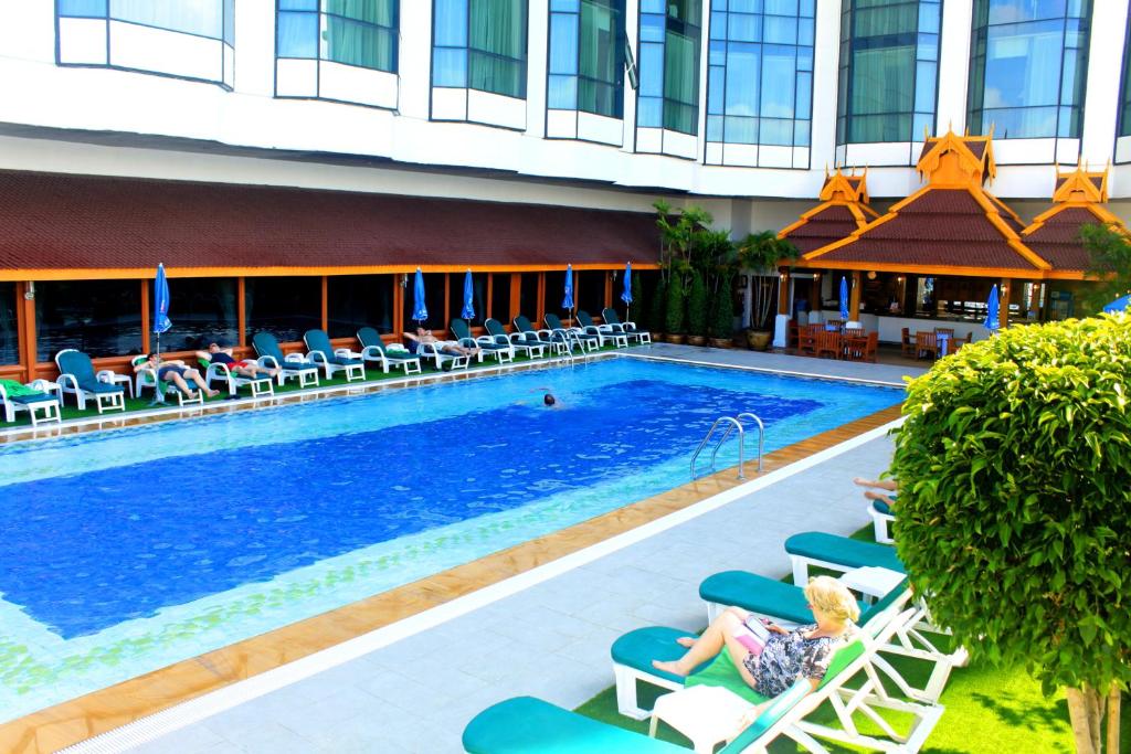 A large outdoor pool bordered by loungers and the hotel’s Thai-style dining pavilion.
