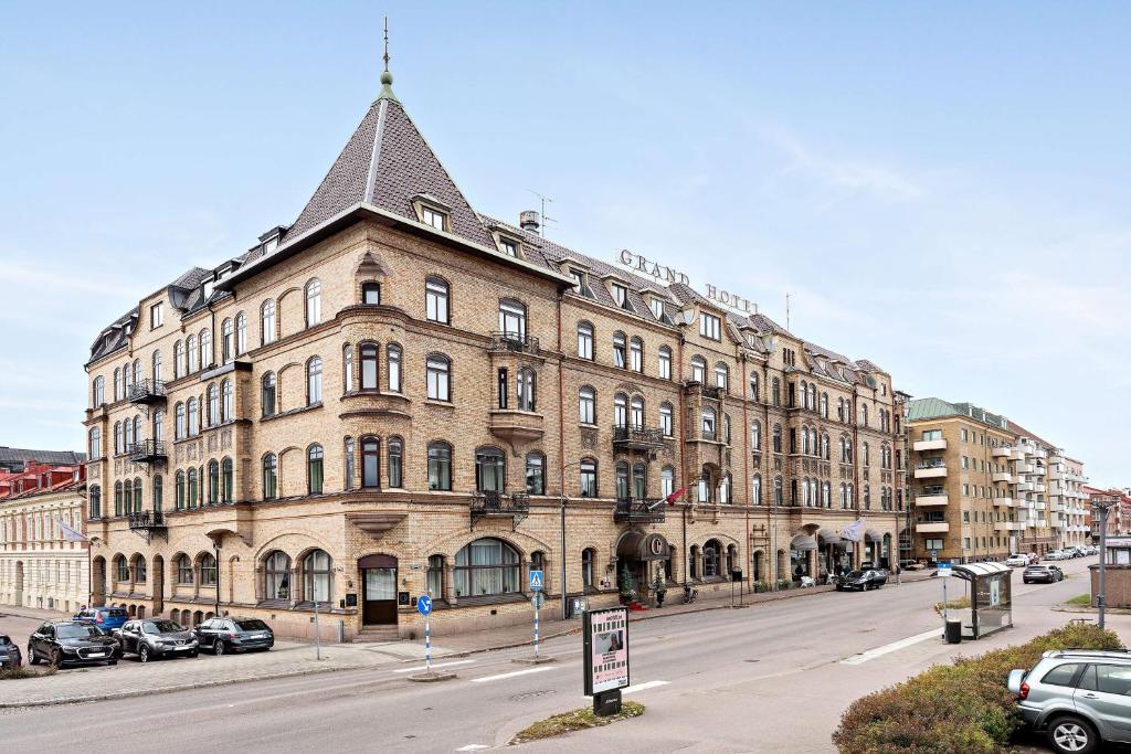 ein großes Gebäude auf einer Straße mit vor der Tür geparkt in der Unterkunft Best Western Plus Grand Hotel in Halmstad
