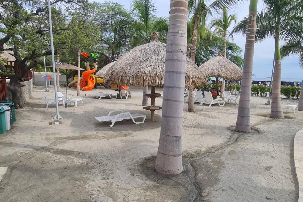 a beach with chairs and straw umbrellas and a playground at Apartamento Cautivador SAMARIA CLUB DE PLAYA con Salida Directa Al Mar y Sus Hermosas Playas de Pozos Colorados Santa Marta in Santa Marta