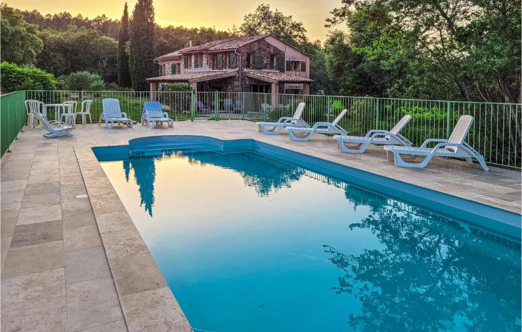 une piscine avec des chaises et une maison en arrière-plan dans l'établissement Amazing Home In Gonfaron With Outdoor Swimming Pool, à Gonfaron