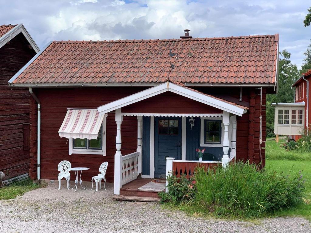 Holiday home Tällberg II في تالبيرغ: منزل احمر صغير مع طاولة وكراسي