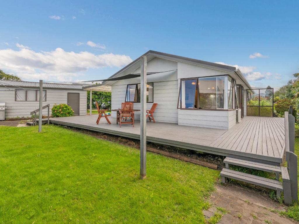 a small white house with a wooden deck at Treasure on Chestnut - Tairua Holiday Home in Tairua