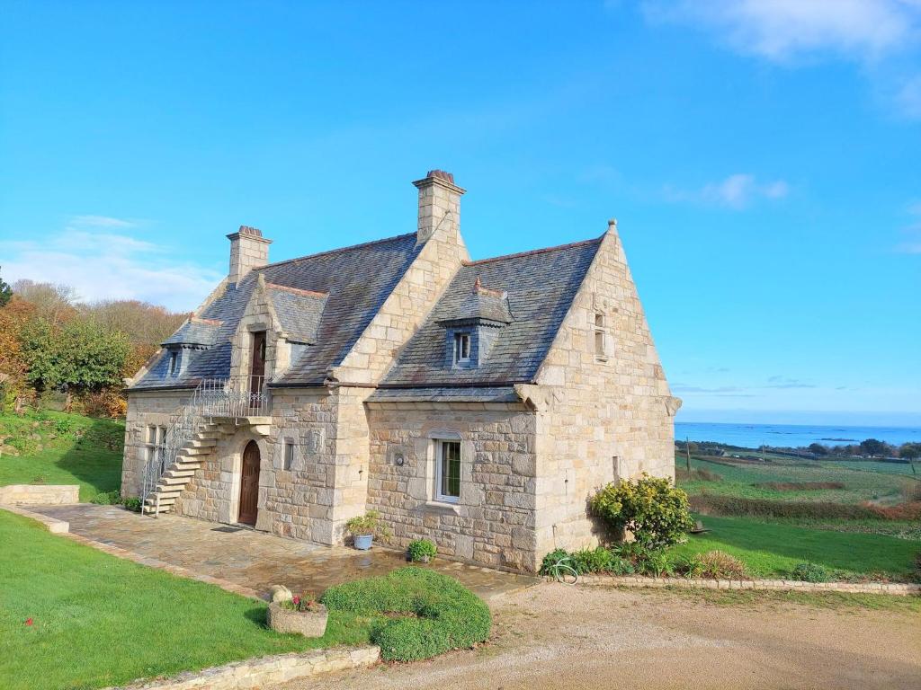 una vieja casa de piedra sentada en la cima de un campo en Breton granite stone house with fantastic sea views, en Saint-Pol-de-Léon