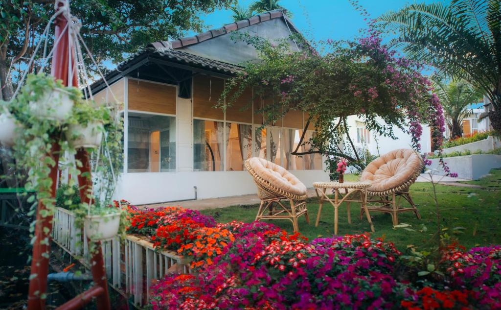 a house with two chairs and flowers in the yard at Vườn Pháp 3 Homestay in Buon Ma Thuot