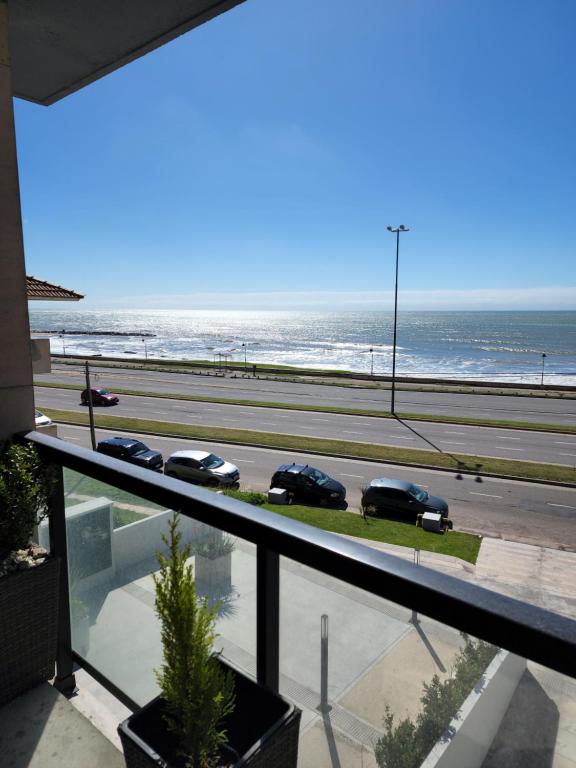 vistas a una playa con coches aparcados en la carretera en Depto premium frente al mar, cochera y piscina!! en Mar del Plata
