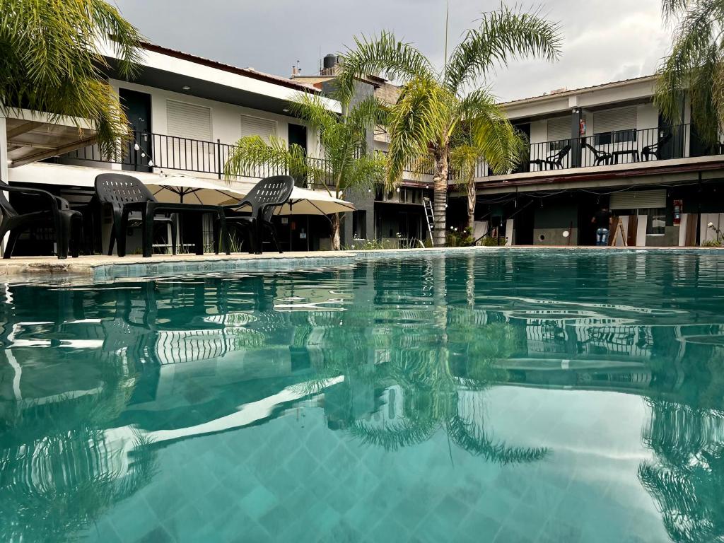 una piscina frente a un edificio con palmeras en Posada del Angel en Villa Carlos Paz